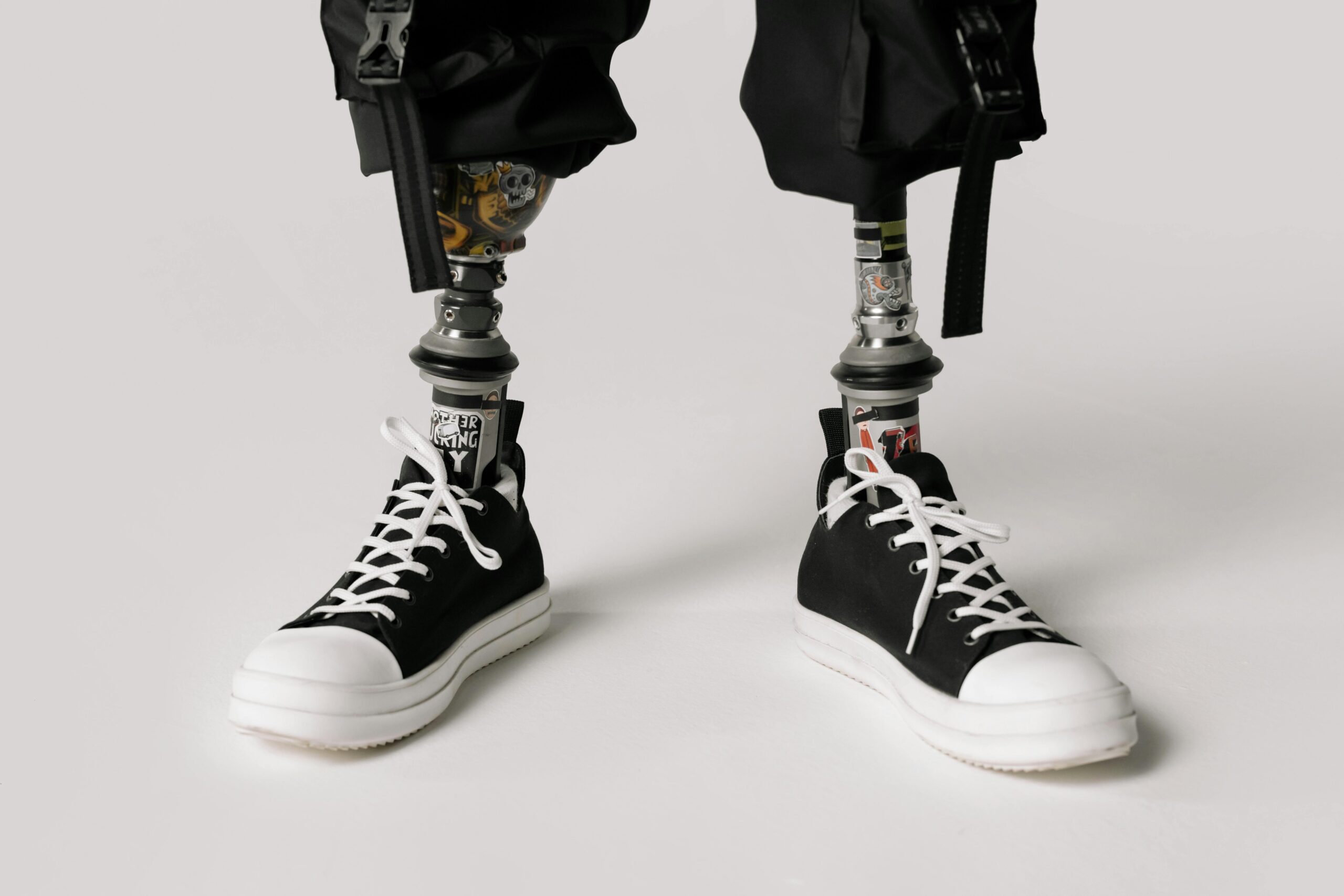Close-up of modern prosthetic legs wearing stylish sneakers on a white background.